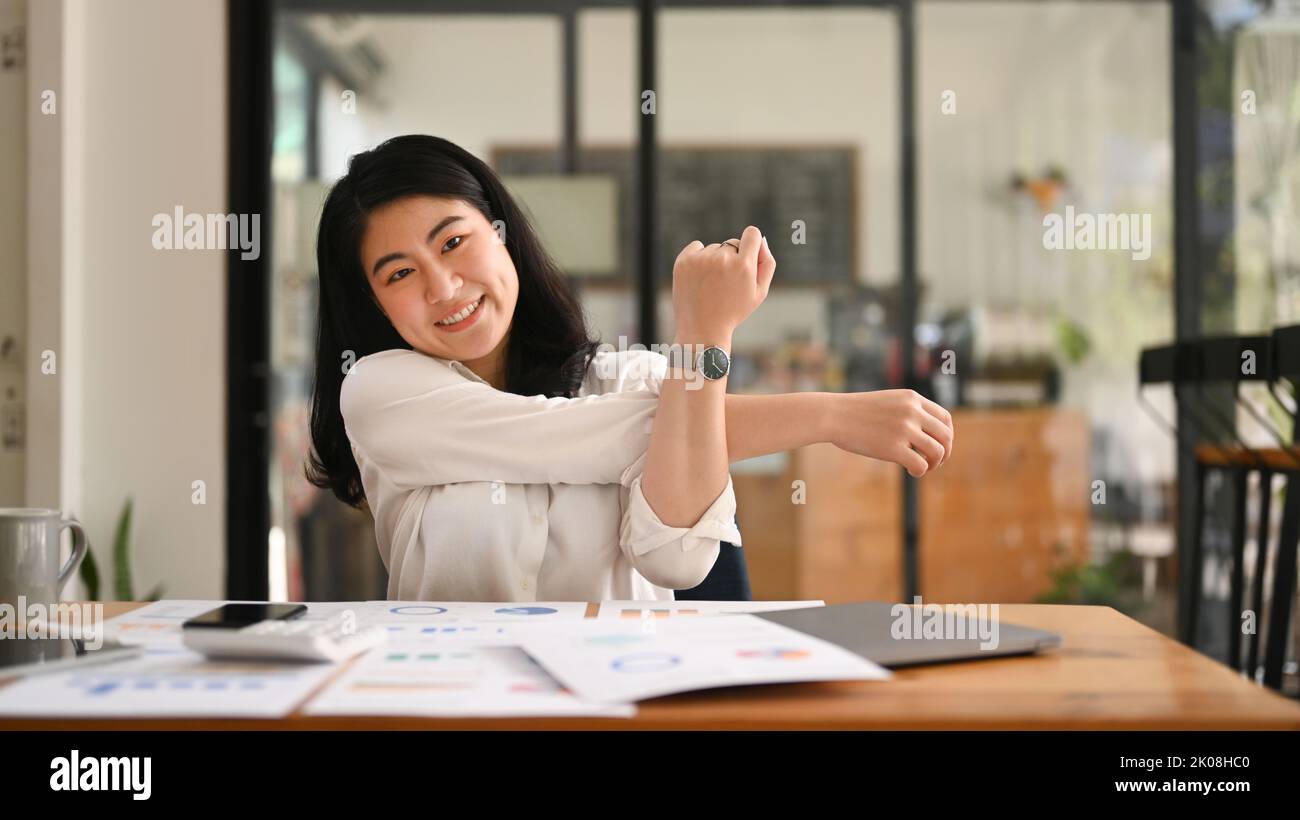 Happy female employee relaxing at work, reclining back in chair and