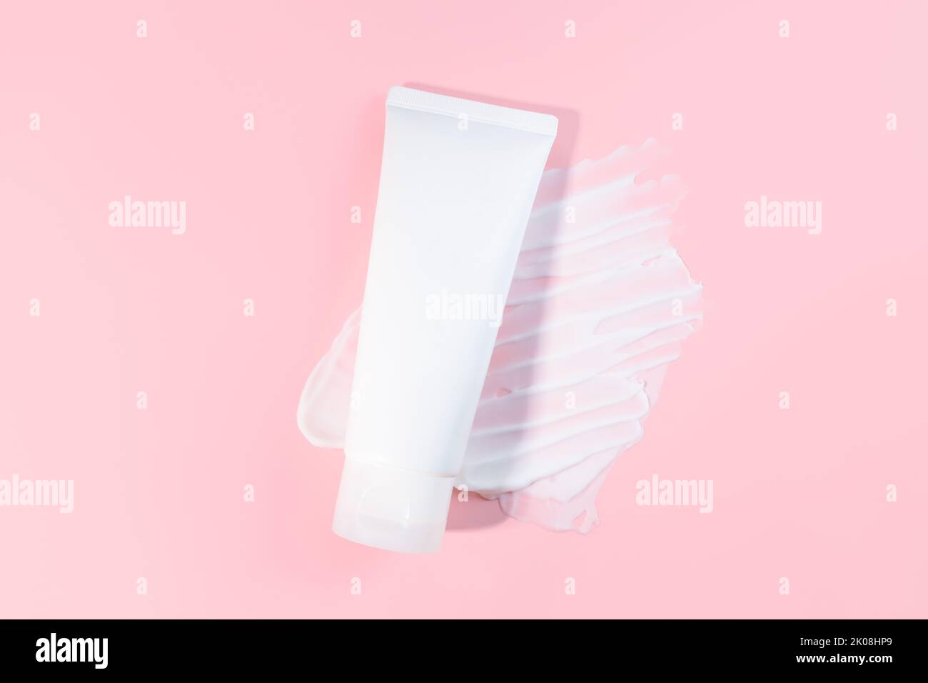 White squeeze bottle plastic tube and moisturizer smear texture on pink