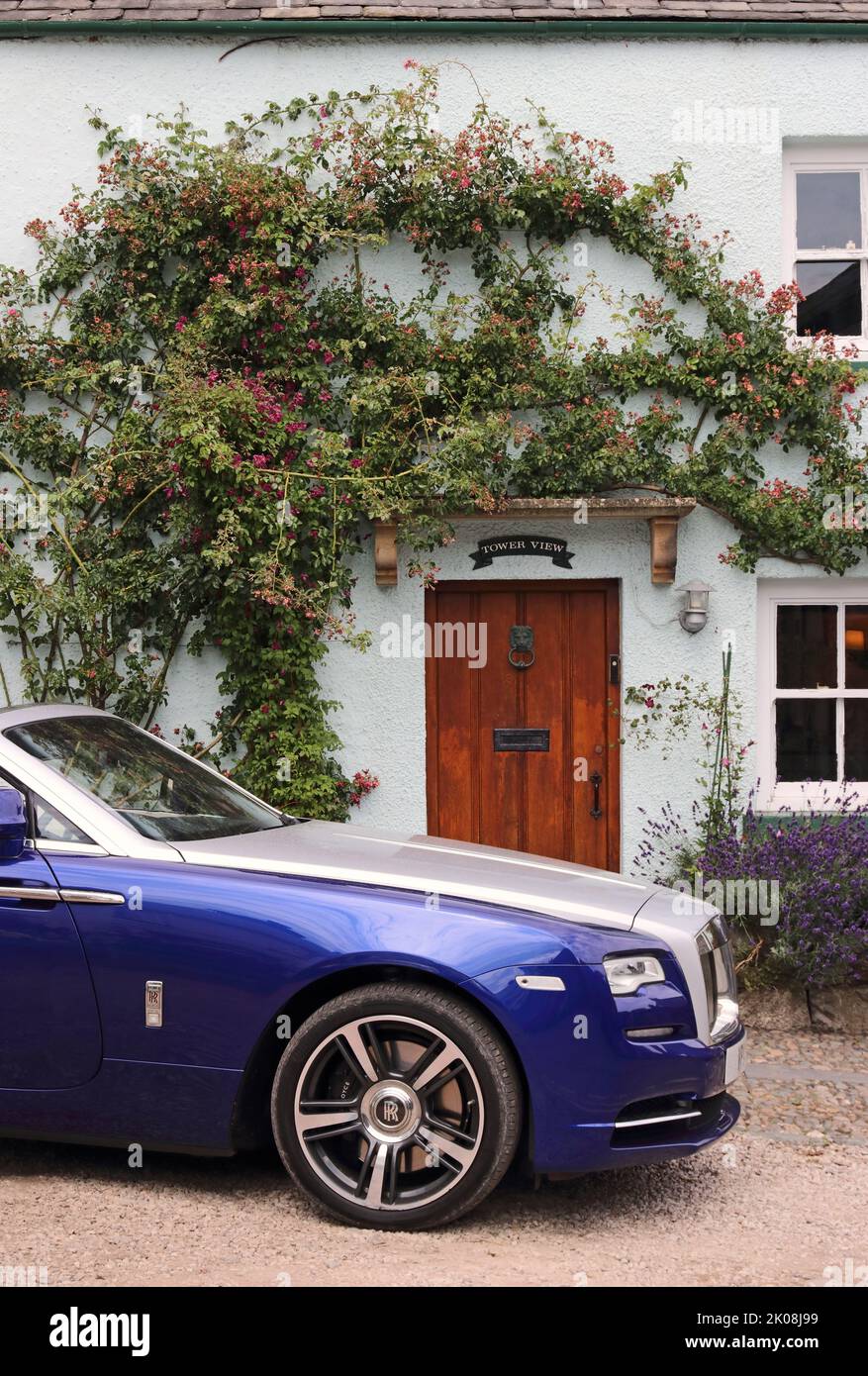 Blue and silver Rolls Royce Dawn convertible parked outside country cottage Stock Photo