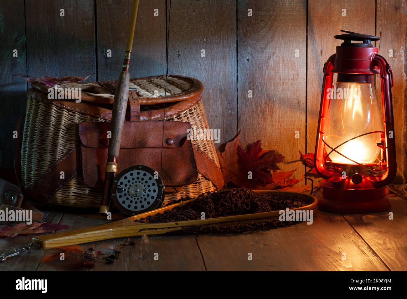 Vintage fly fishing rod creel and net with lantern on old grunge wood background Stock Photo