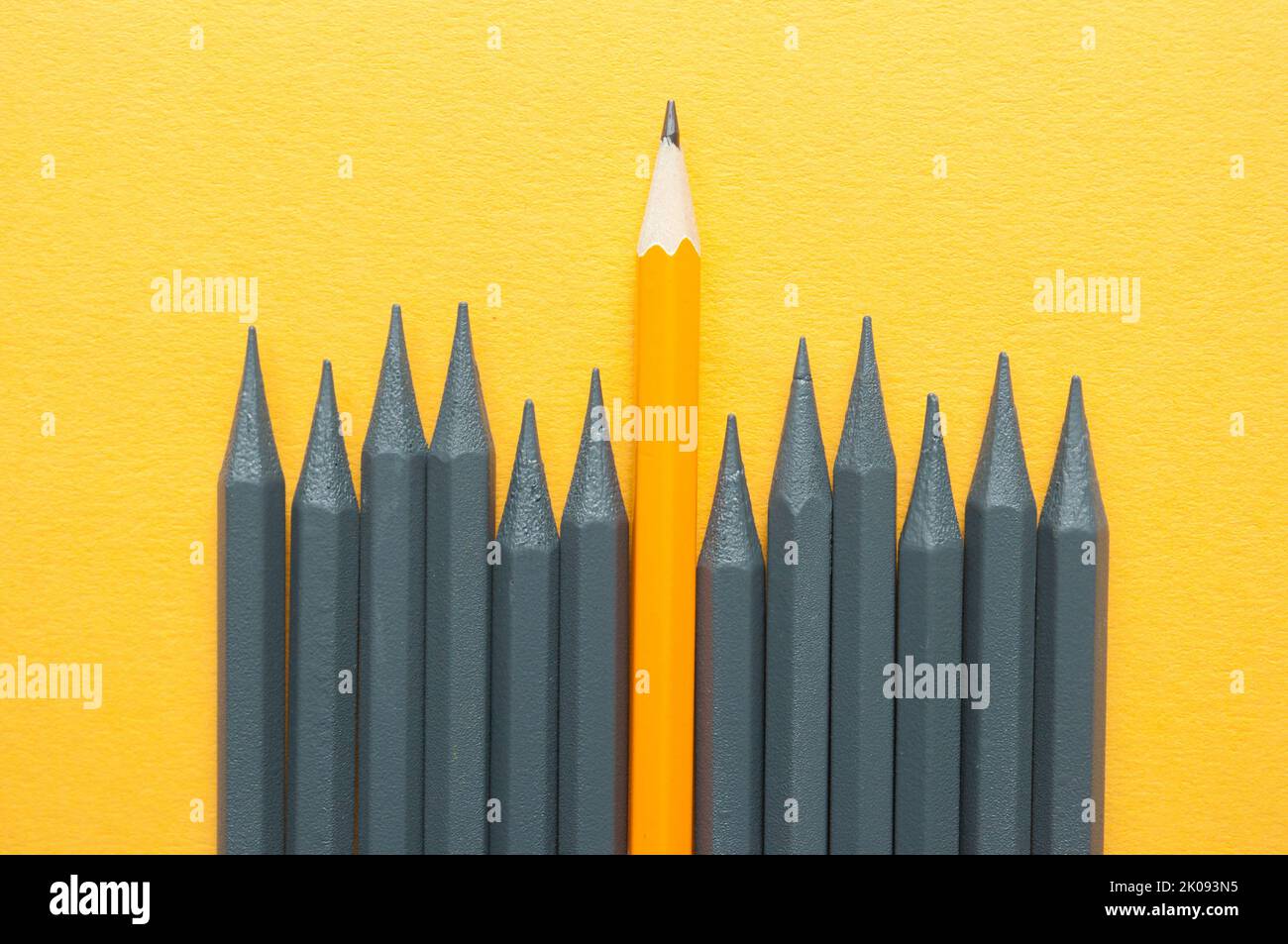 Orange pencil standing out amongst grey pencils Stock Photo