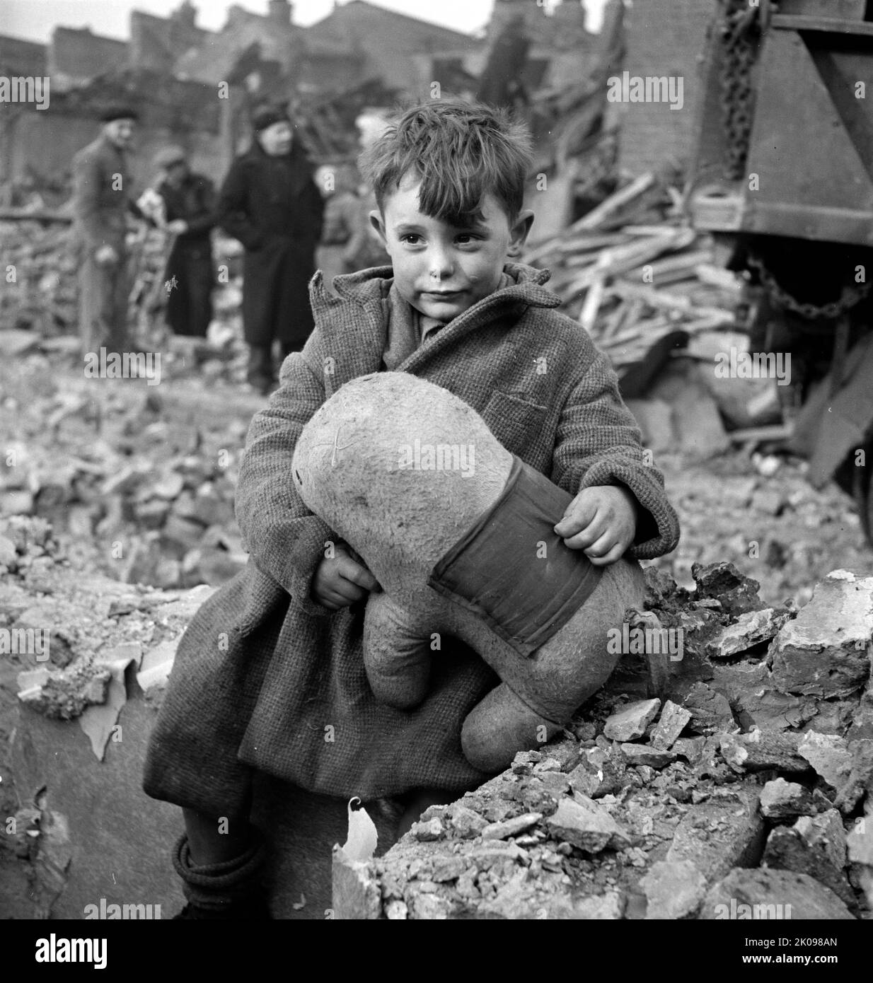 Abandoned boy holding a stuffed toy animal amid ruins following German aerial bombing of London, 1941. Stock Photo