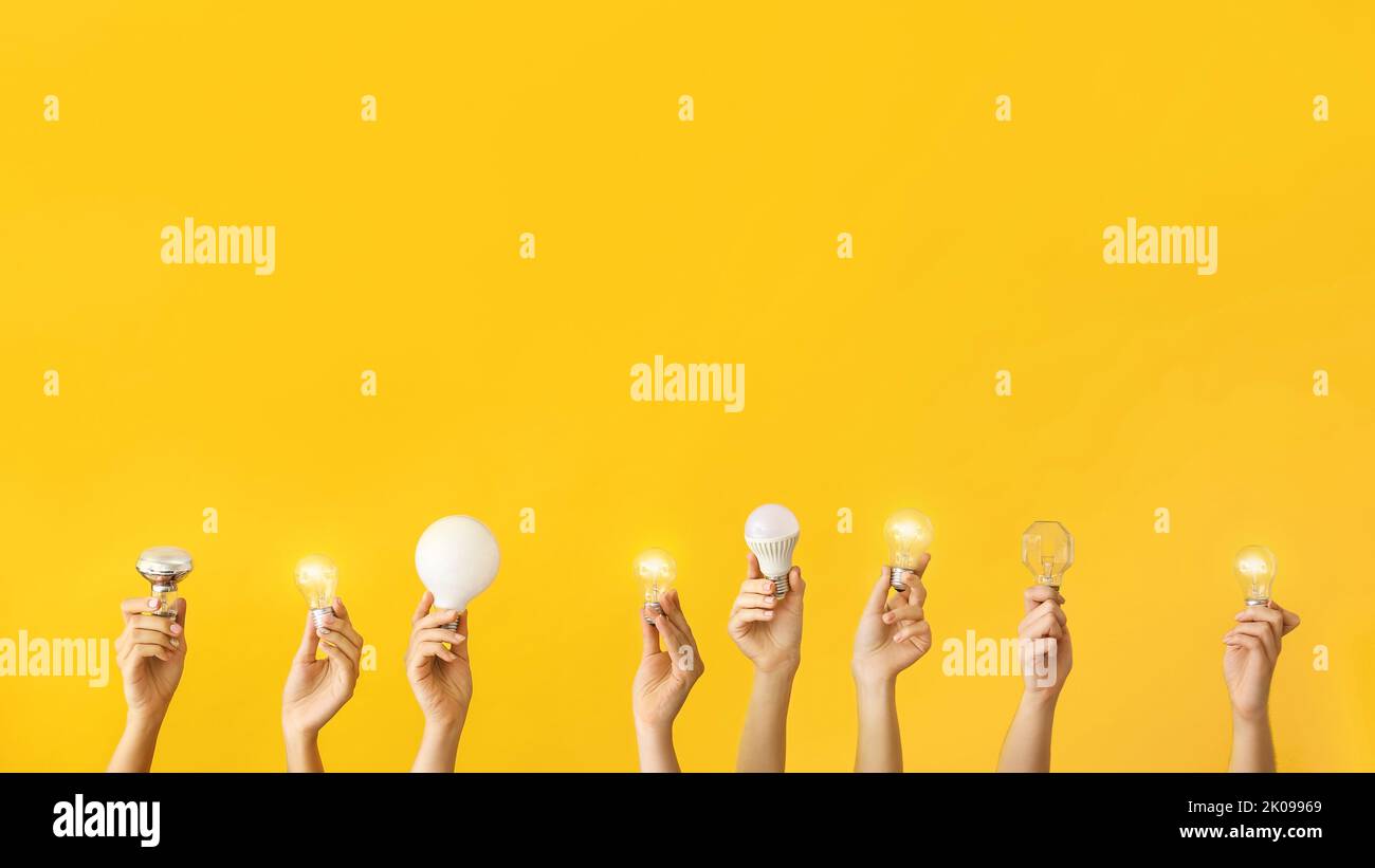 Many hands with different light bulbs on yellow background Stock Photo