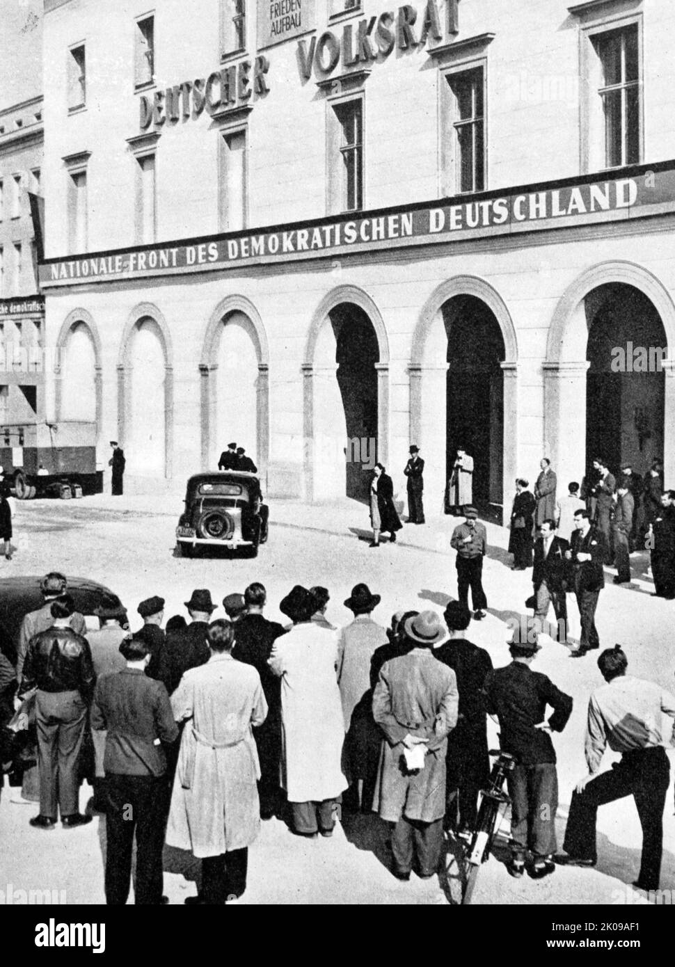 Berliners watching the arrival of the newly-elected members of the Lander-Kammer of the new East German government. The Chamber of States was the upper chamber of the bicameral legislature of the German Democratic Republic (East Germany) from its founding in 1949 until 1952, at which time it was largely sidelined, when the five Lander (states) of East Germany ceased to exist and were replaced with smaller administrative regions. Stock Photo