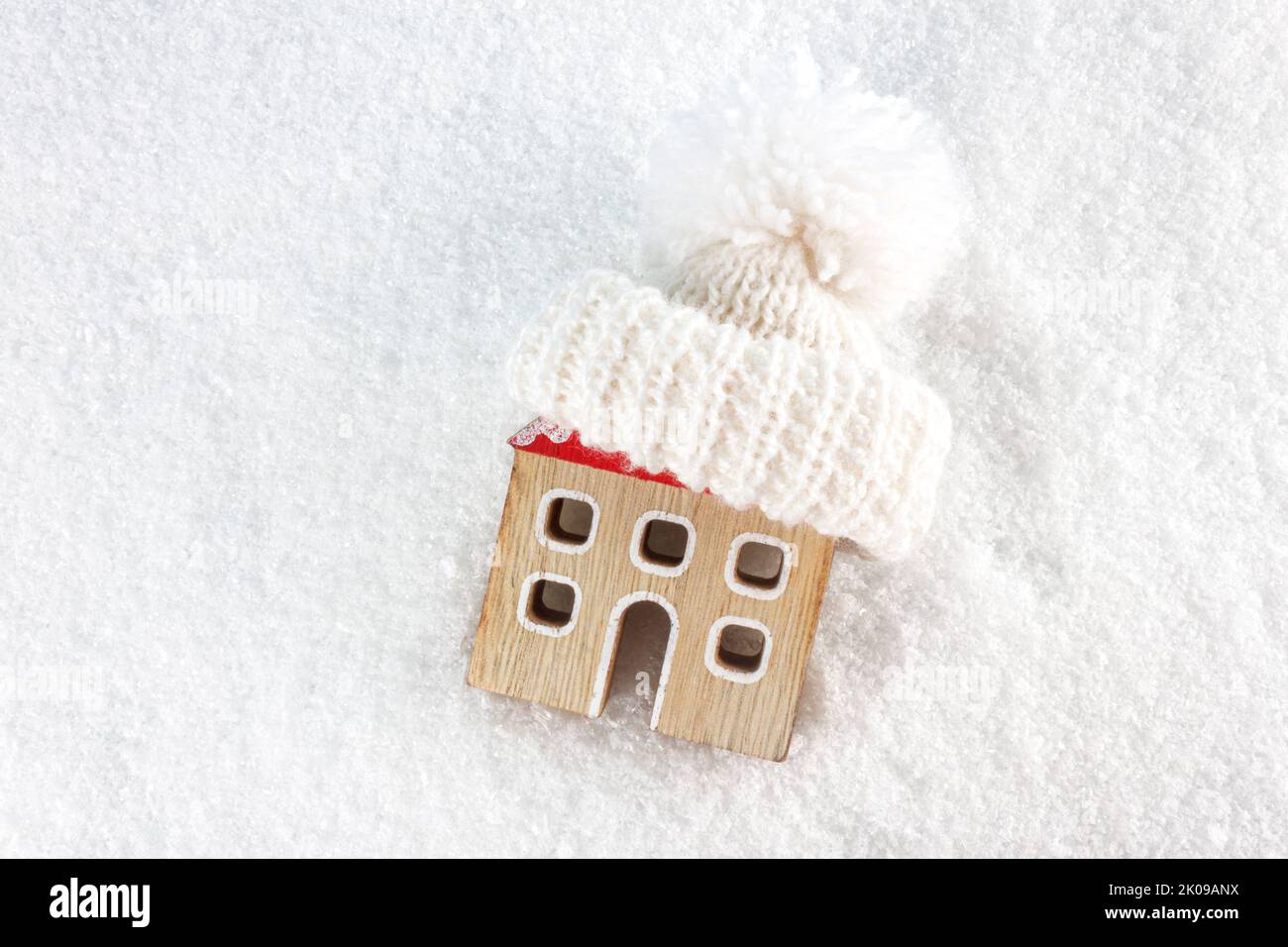 Figure of house and warm clothes on the snow background. Heating season concept. European energy crisis concept. Copy space. Top view. Stock Photo