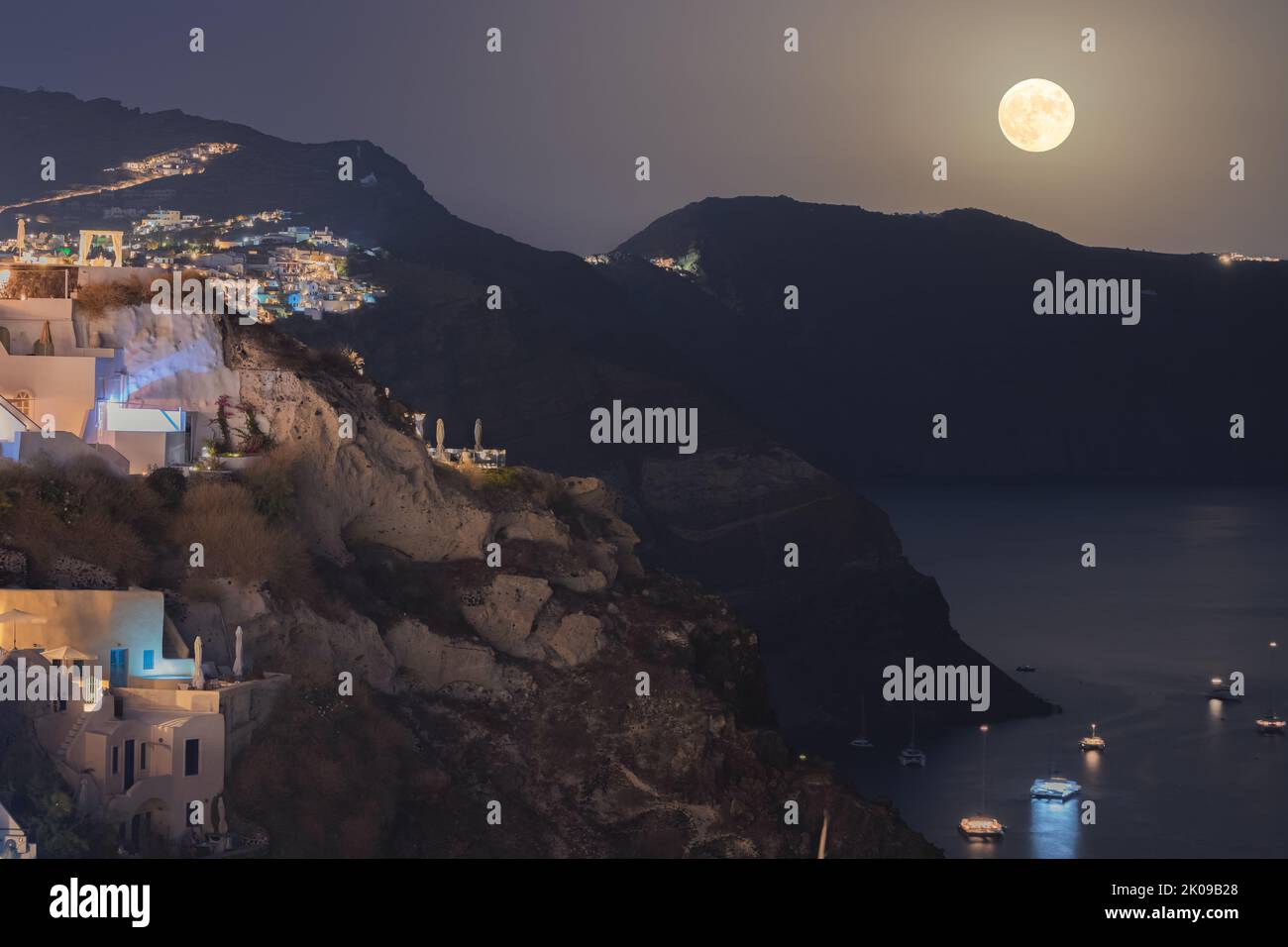 Dramatic full harvest moon rise over the caldera and Greek Island of Santorini on September 10, 2022 taken from the coastal village of Oia in Greece. Stock Photo