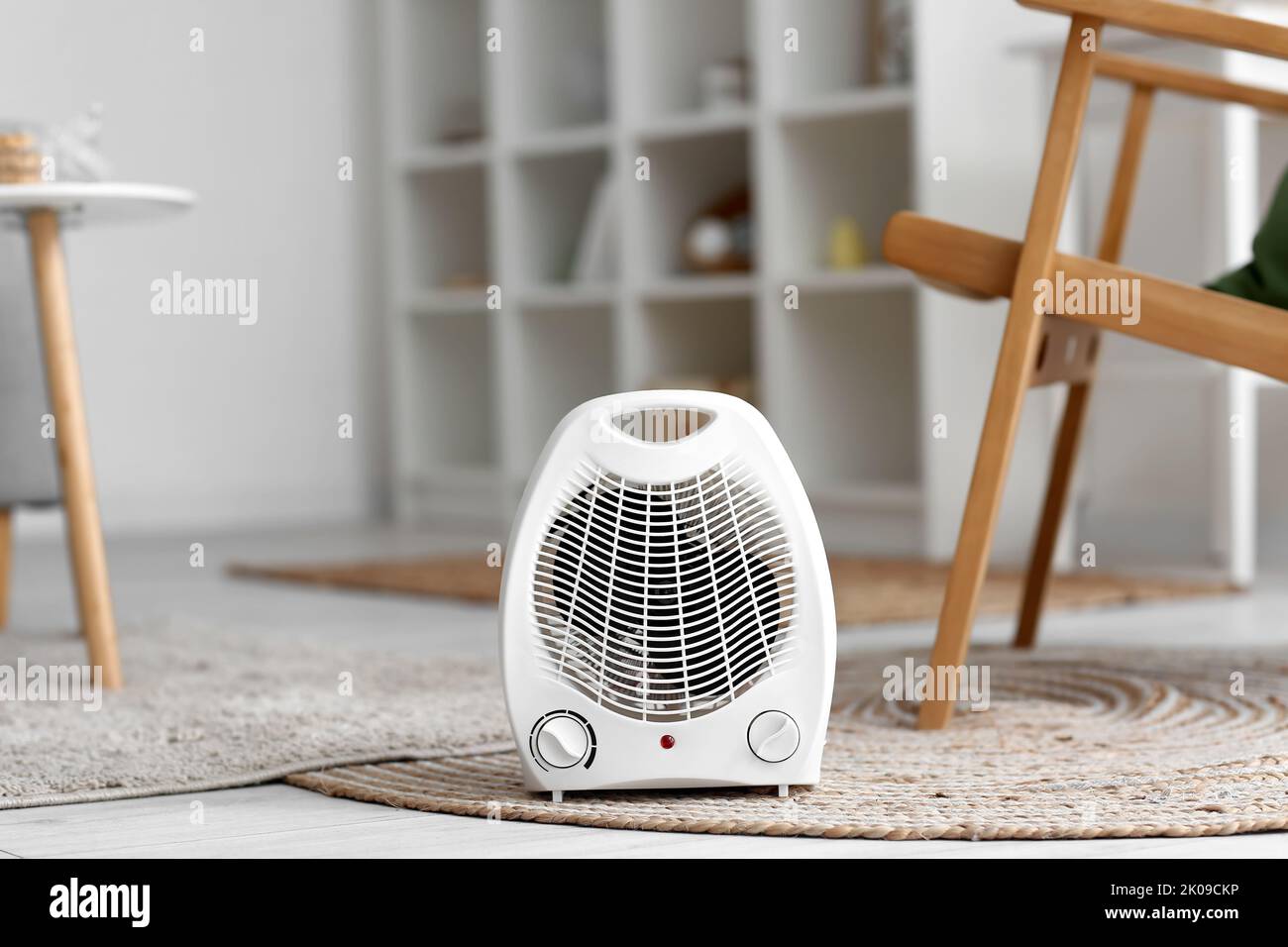 Electric fan heater on rug in living room Stock Photo