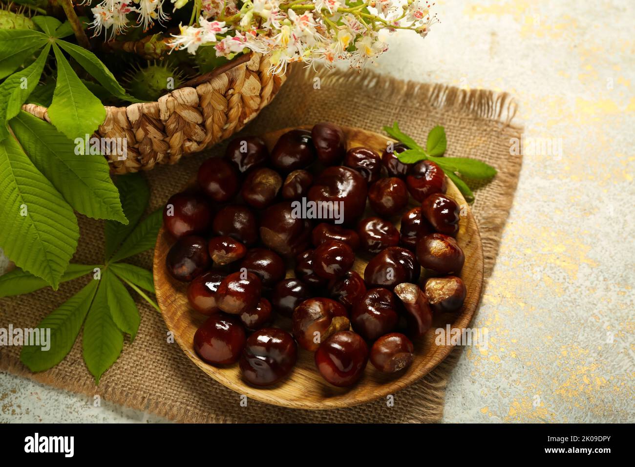 Plate with fresh chestnuts on light background Stock Photo
