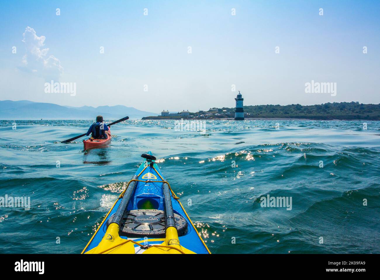 Sea kayaking near Trwyn Du Lighthouse, also known as Penmon Lighthouse off Puffin Island on the coast of Anglesey, Wales UK Stock Photo