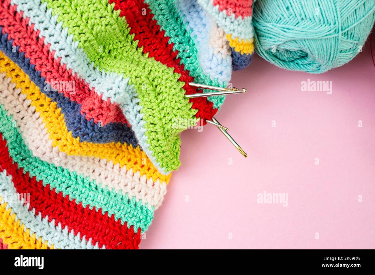 Multicolored crochet lines pattern with hooks and spool, flat lay close up backdrop Stock Photo