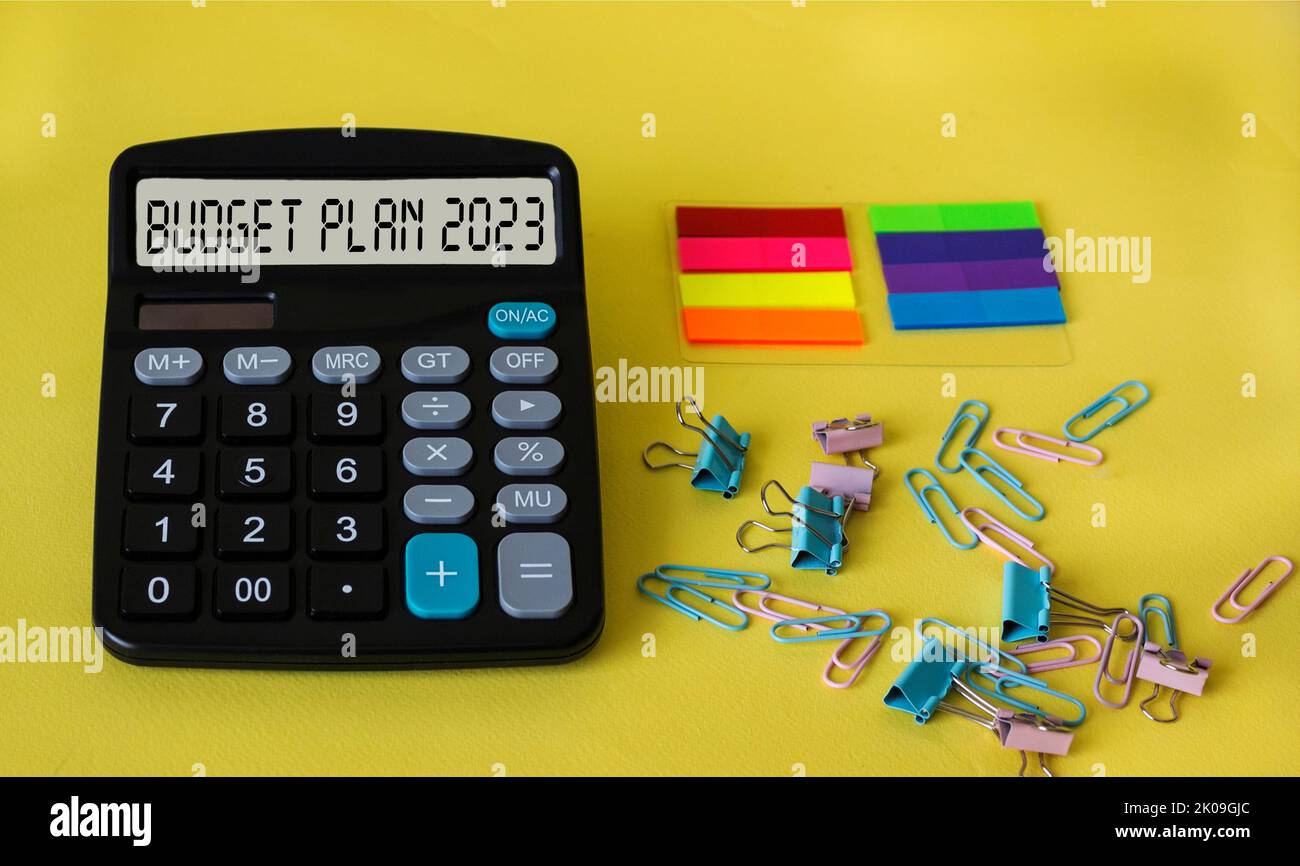 budget plan 2023. text in on calculator display on yellow background with various stationery Stock Photo