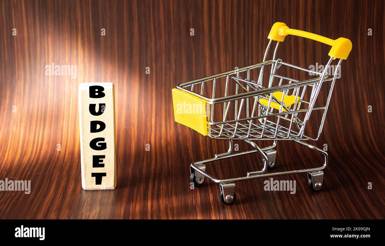 Wooden block with the word BUDGET on a wooden table and with an empty basket Stock Photo