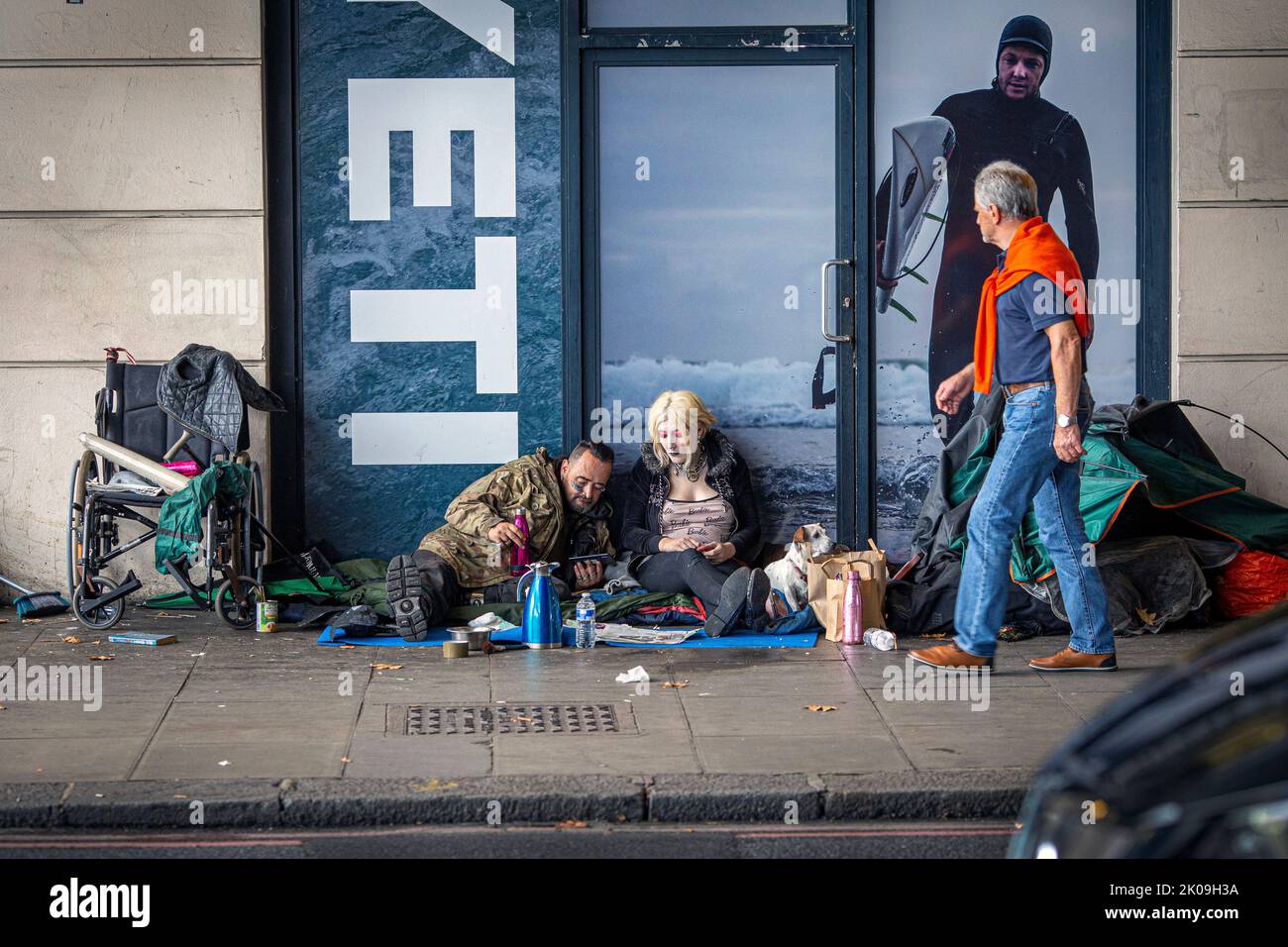 London UK 10th September 2022 - Young homeless couple watch King Charles III accession speech on smartphone in and a member of the public can be seen walking past.King Charles III was also proclaimed as monarch today.Photo Horst A. Friedrichs Alamy Live News Stock Photo