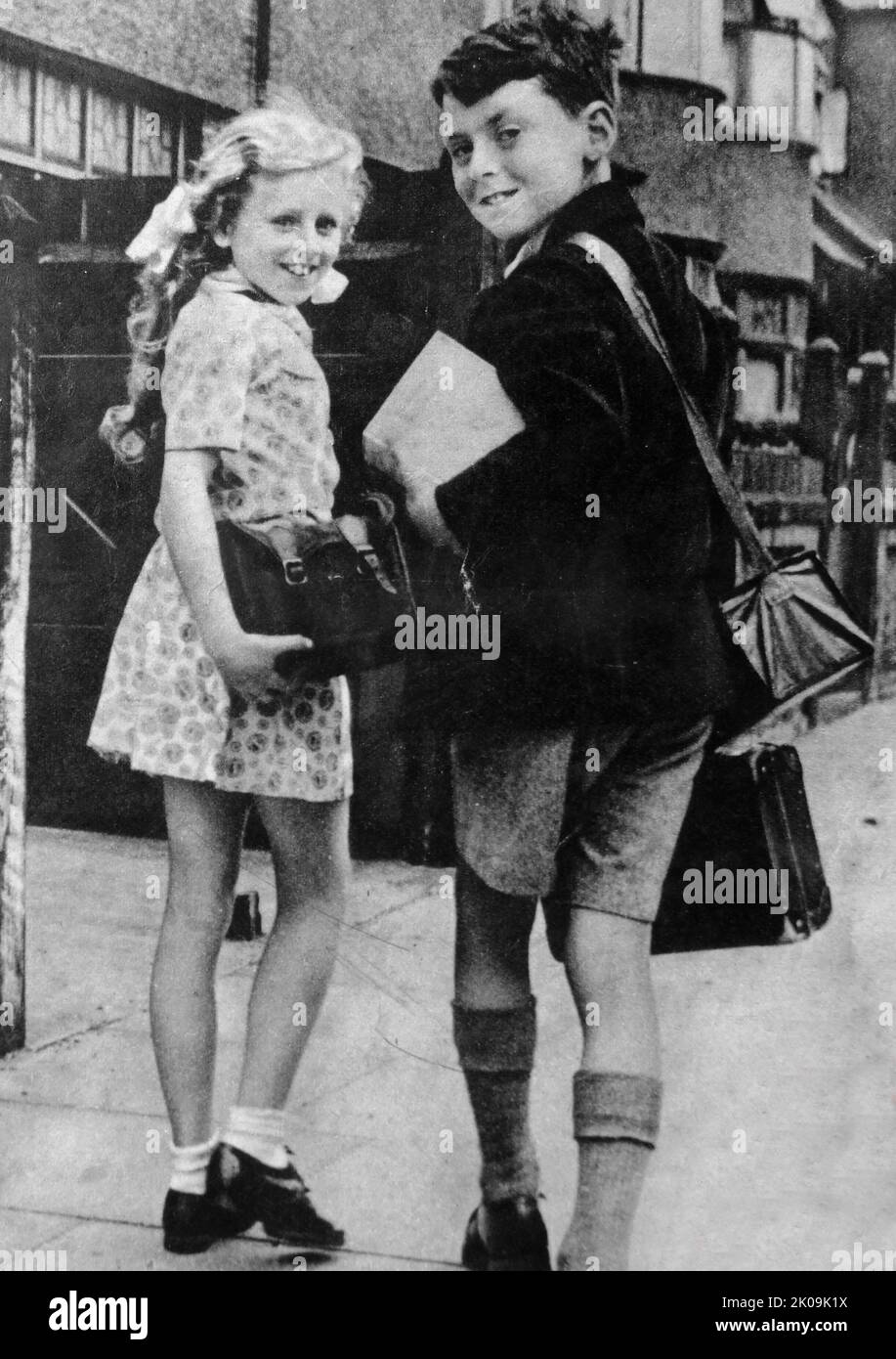 Brother and sister walk to school during World War II, London, England