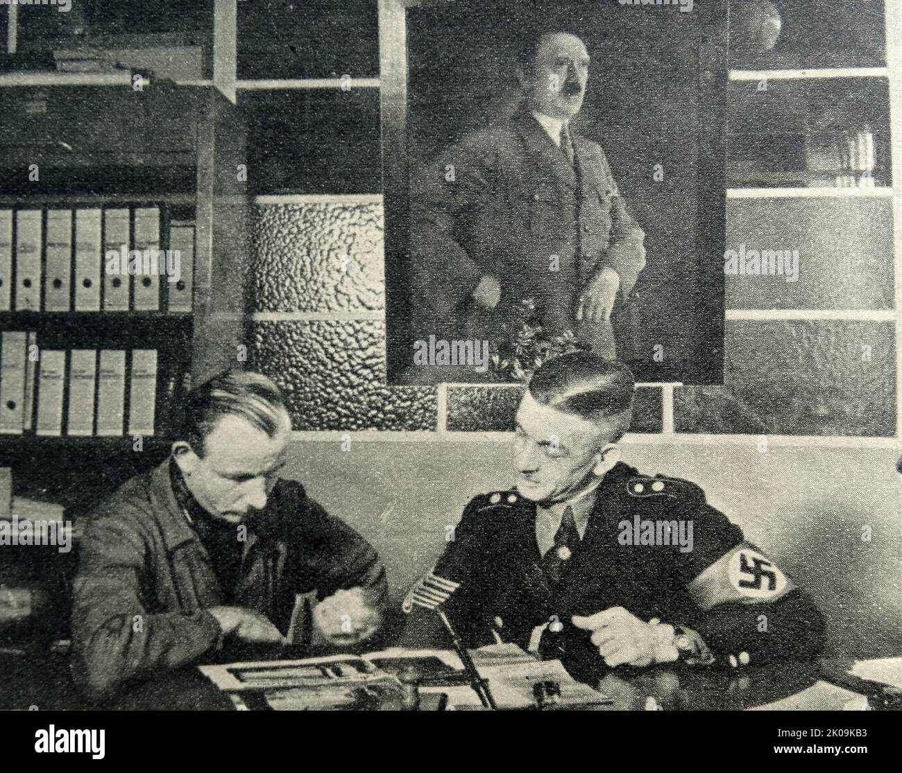 Nazi Storm Trooper Johann Laub consults holiday literature helped by a Nazi official. The Sturmabteilung was the Nazi Party's original paramilitary wing. It played a significant role in Adolf Hitler's rise to power in the 1920s and 1930s. Stock Photo