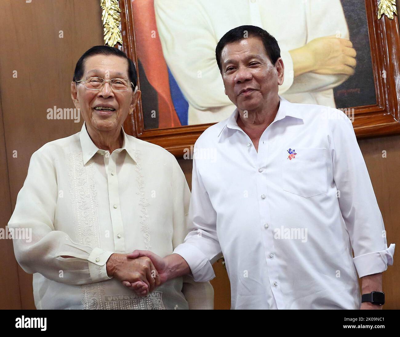 Phillipines President Rodrigo Roa Duterte shakes hands with former Senator Juan Ponce Enrile as they pose near the President's portrait following their meeting in Malacanan Palace on March 1, 2017. Stock Photo