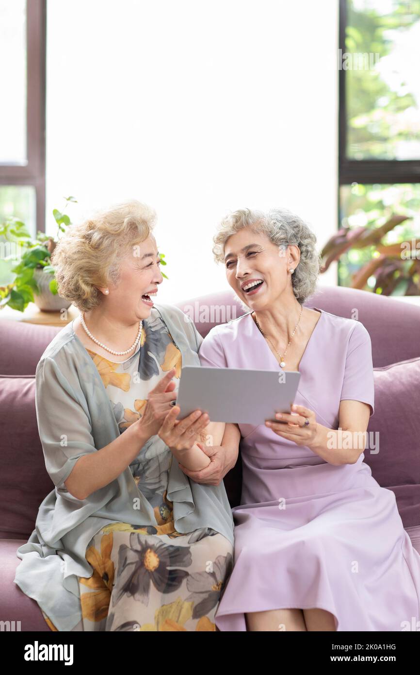 Happy senior Chinese friends using digital tablet at home Stock Photo