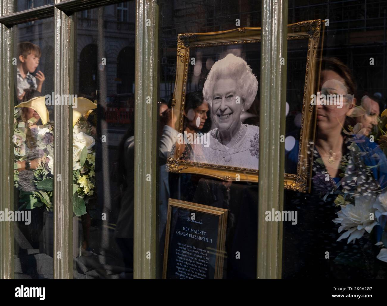 A shop close to  Buckingham Palace displays a photograph in memory of  Queen Elizabeth II   Members of the public gather to lay flowers in green park Stock Photo