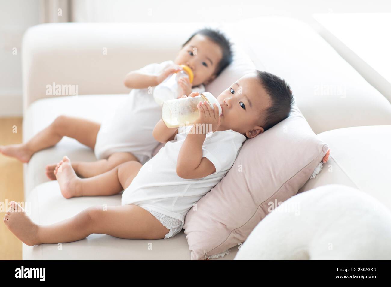 brother feeding little sister with milk or cereal with a bottle Stock Photo