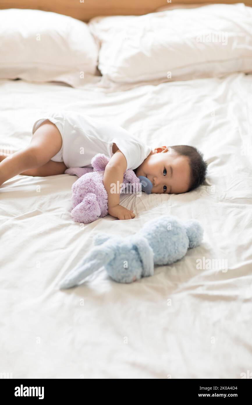 Cute Chinese baby lying on bed with pacifier Stock Photo - Alamy