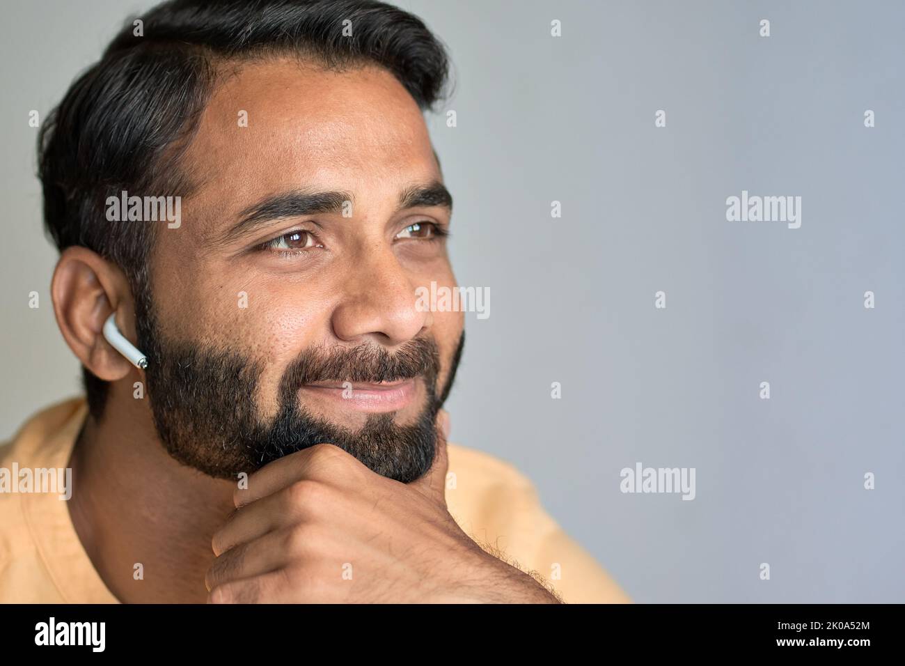 Smiling indian man wearing earbuds listening music or podcast. Closeup Stock Photo