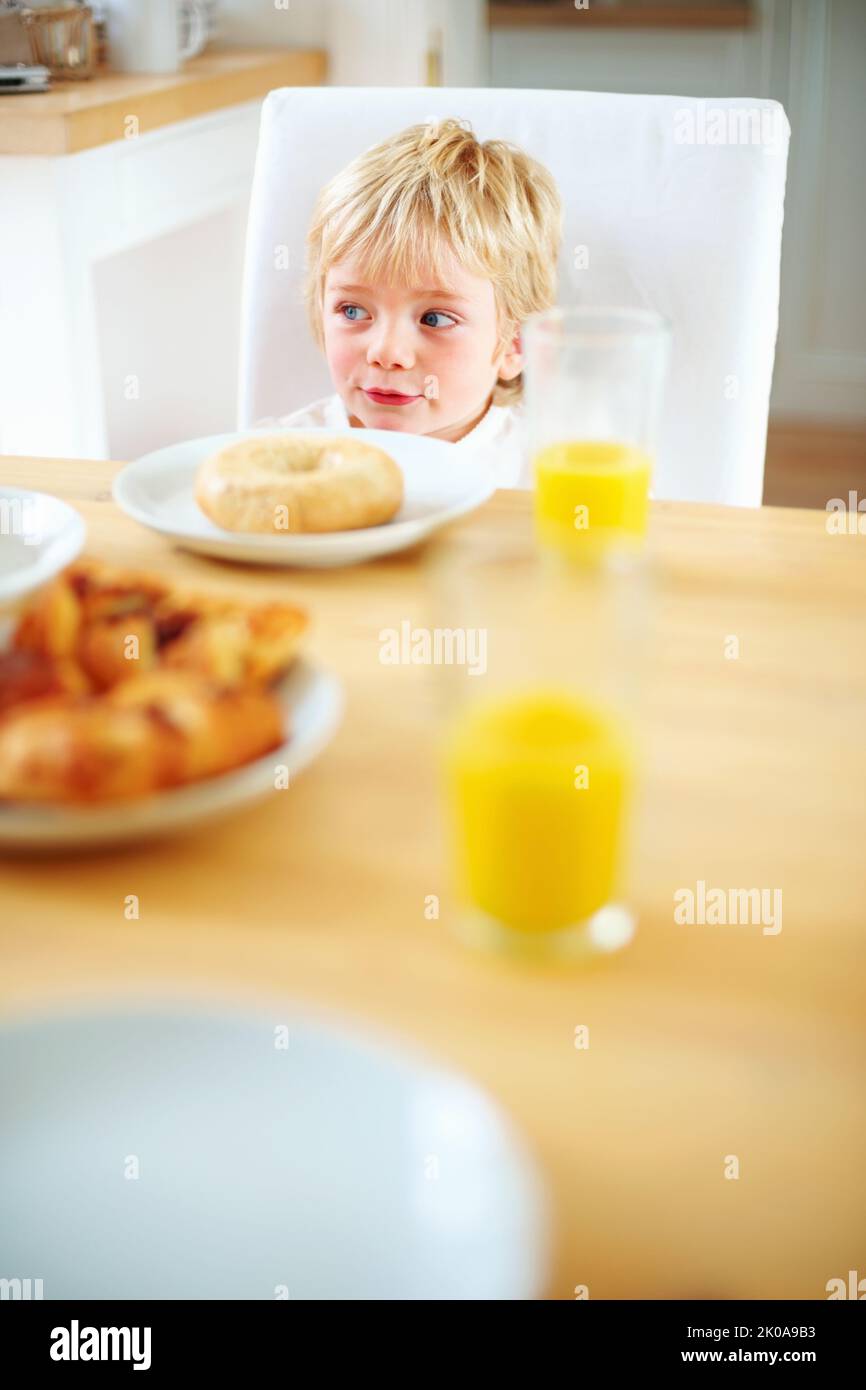 Cute little boy having breakfast with donut and juice on table. Portrait of a cute little boy having his breakfast with donut and juice on table. Stock Photo