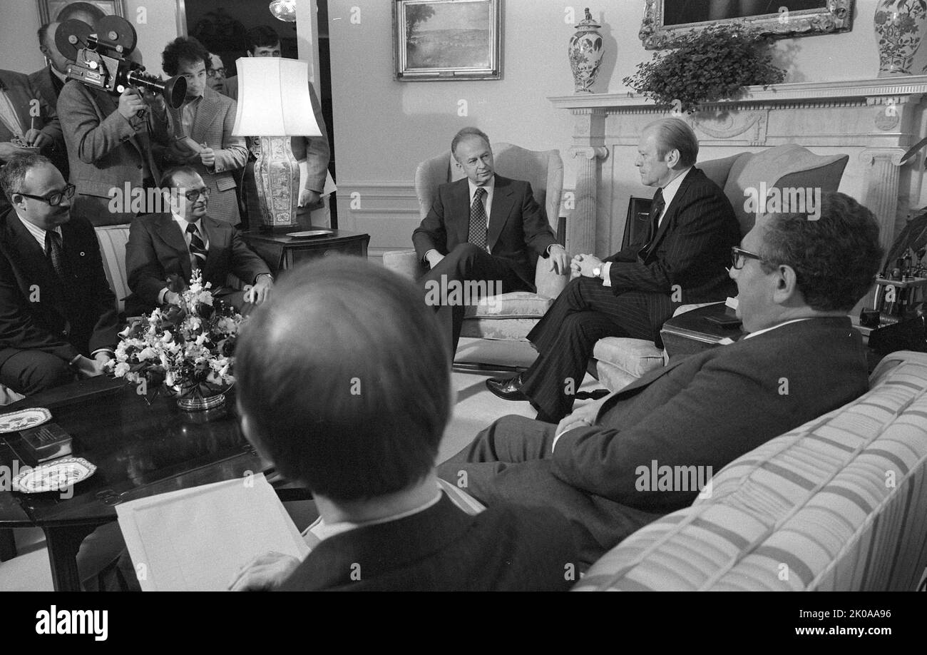 President Gerald Ford (centre) sitting in chair in front of fireplace, with Israeli Prime Minister Yitzhak Rabin (left) and others including U.S. Secretary of State Henry Kissinger (right), at the White House. 1976 Stock Photo