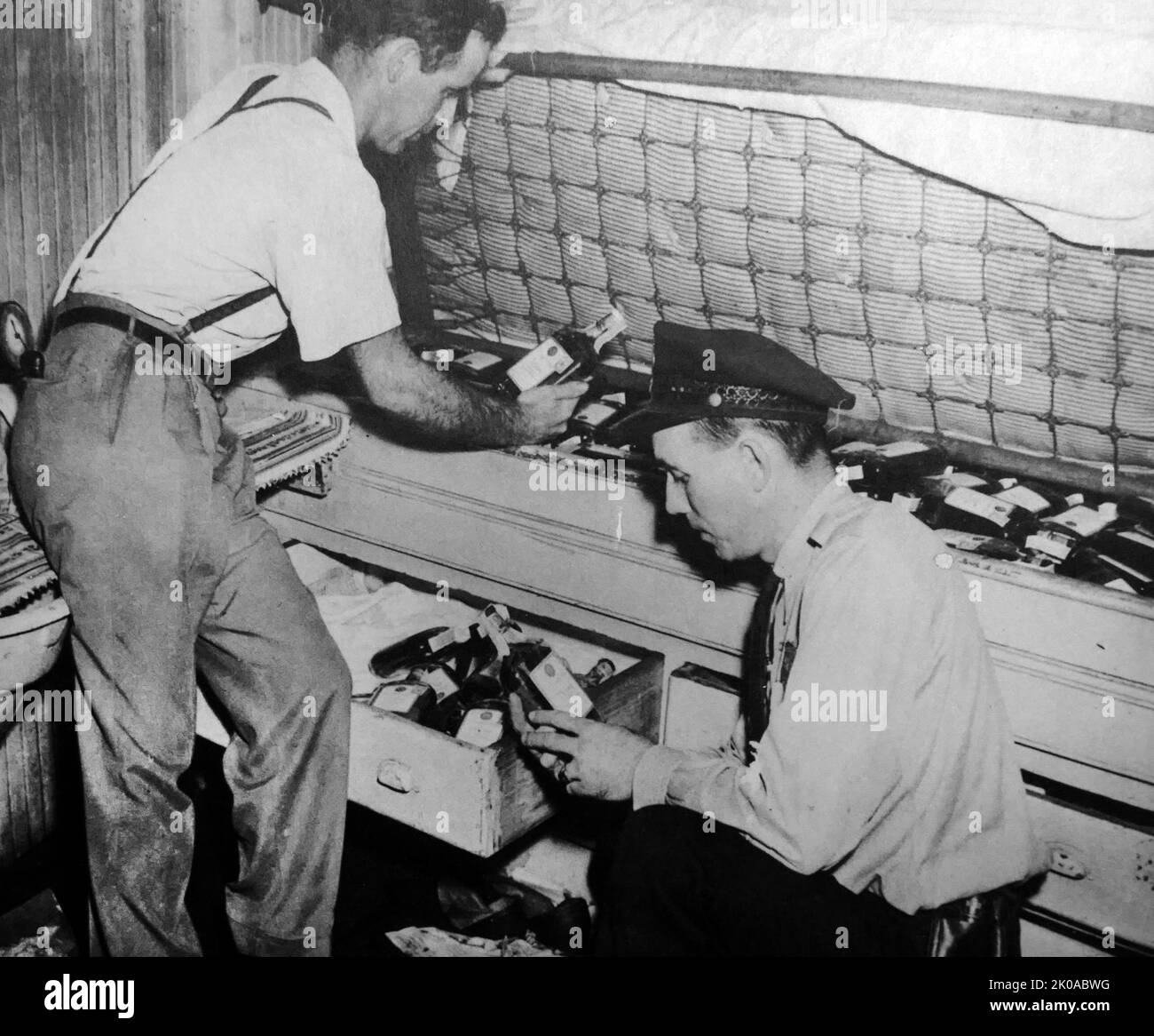 Enforcing prohibition in America. Officials inspect bottles of liquor found under a sailor's mattress on a steamer in Norfolk, Virginia. Prohibition in the United States was a nationwide constitutional ban on the production, importation, transportation, and sale of alcoholic beverages from 1920 to 1933 Stock Photo