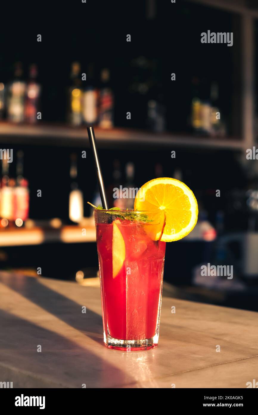 Serving fresh red, purple summer fruit cocktail at bar counter on sunny day. Selected focus, shallow depth of field. Stock Photo