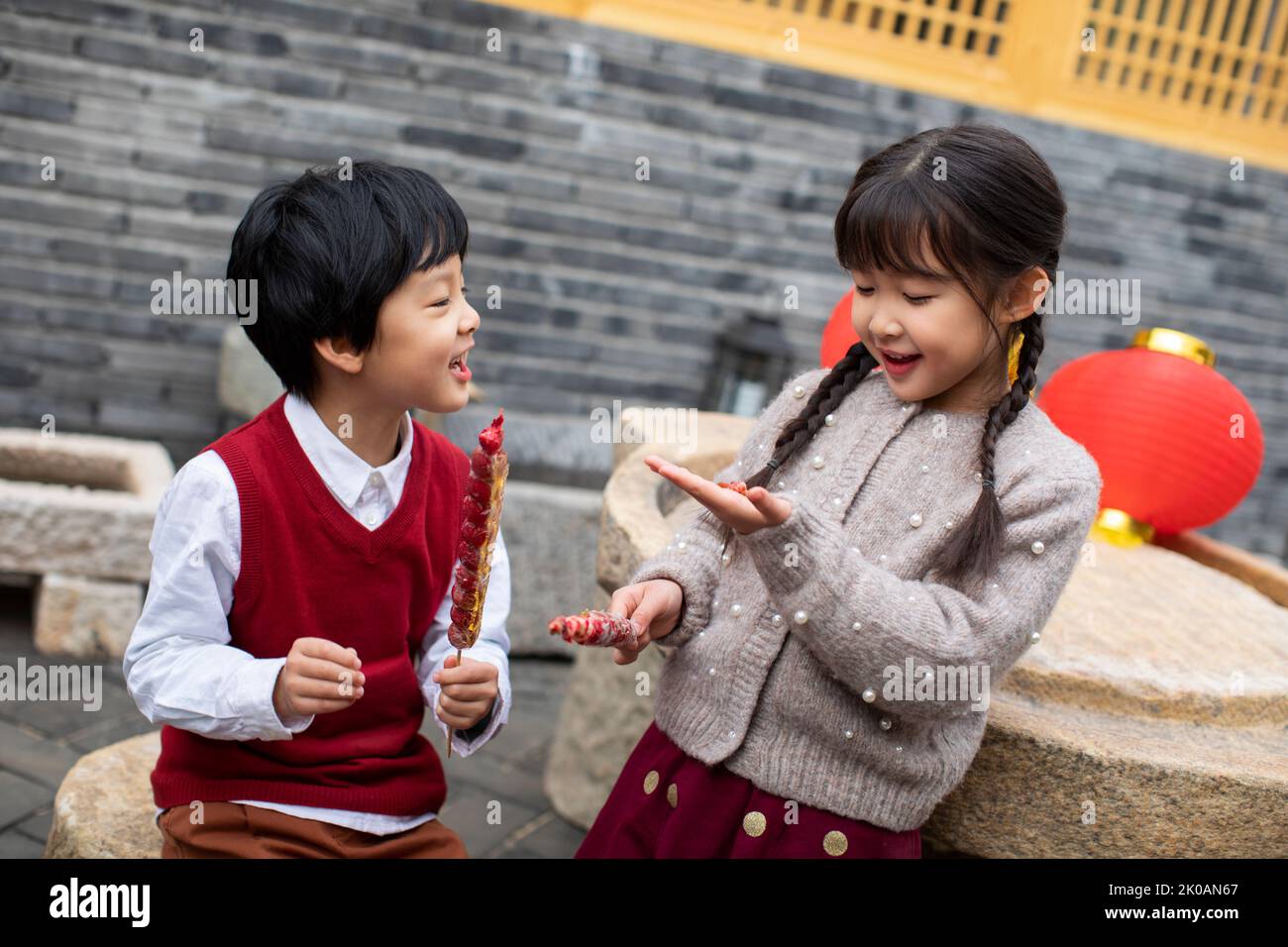 Happy Chinese sibling eating candied haws Stock Photo