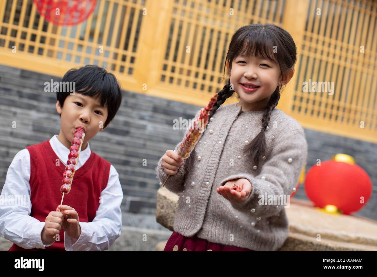 Happy Chinese sibling eating candied haws Stock Photo