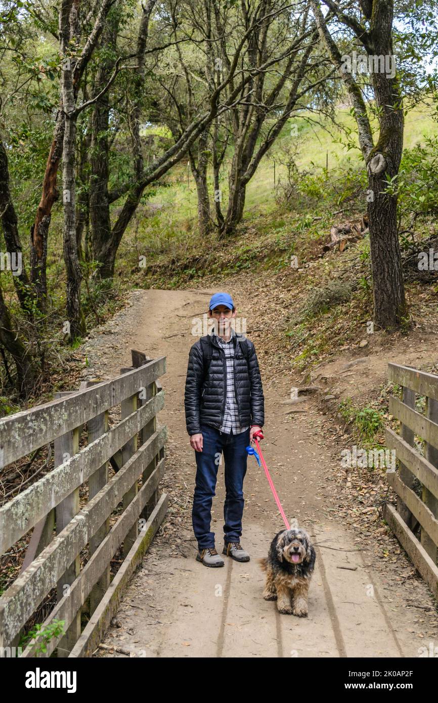 Man walking a dog through a forest in Oakland, California Stock Photo