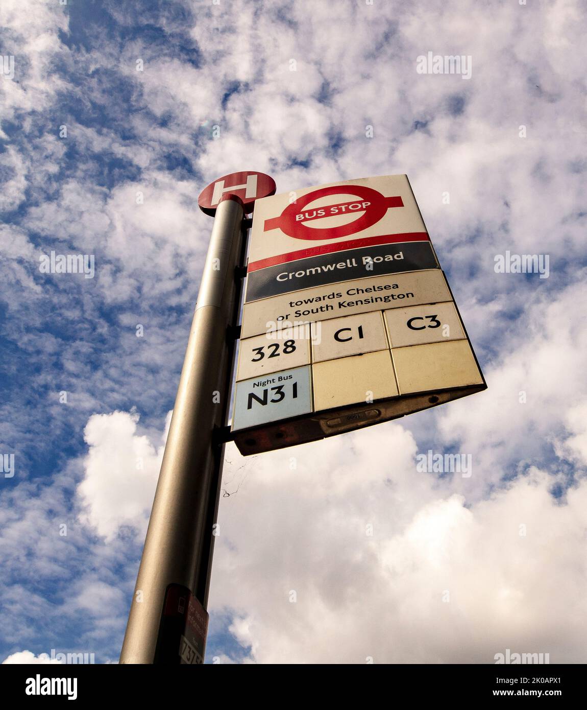 Bus stop sign, 'Cromwell Road', in Kensington, South West London against a dark blue cloudy sky Stock Photo