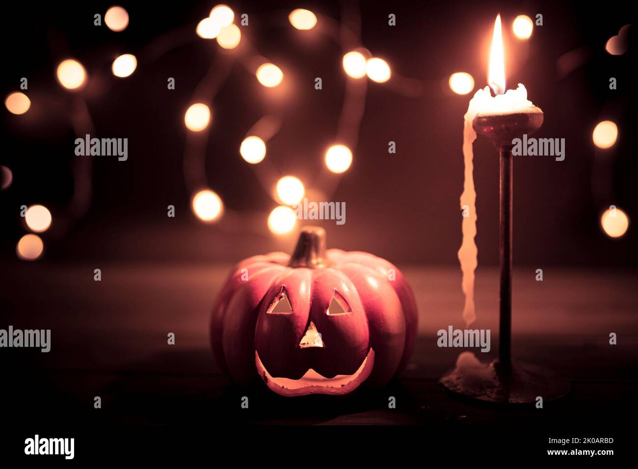 Halloween pumpkin wallpaper with candle and string lights bokeh in the background. Toned vintage colors. Stock Photo