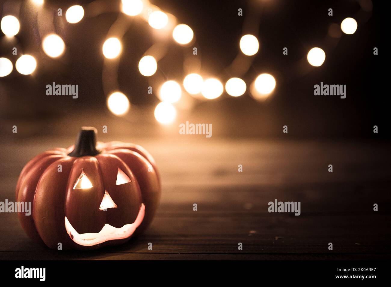 Halloween pumpkin wallpaper with string lights bokeh in the background. Toned vintage colors, copy space. Stock Photo