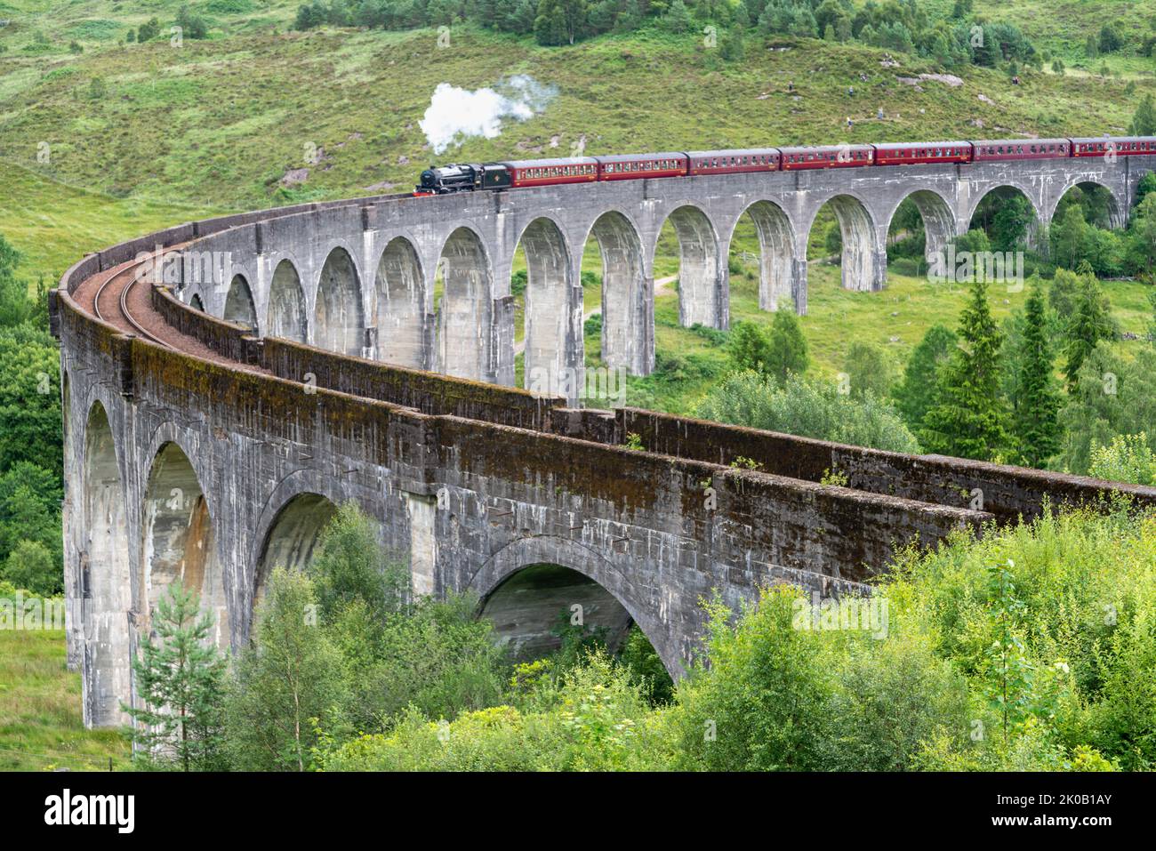 The Jacobite steam locomotive,tourist train,starts to cross the iconic viaduct bridge,on the West Highland Line,popular tourist location landmark,due Stock Photo