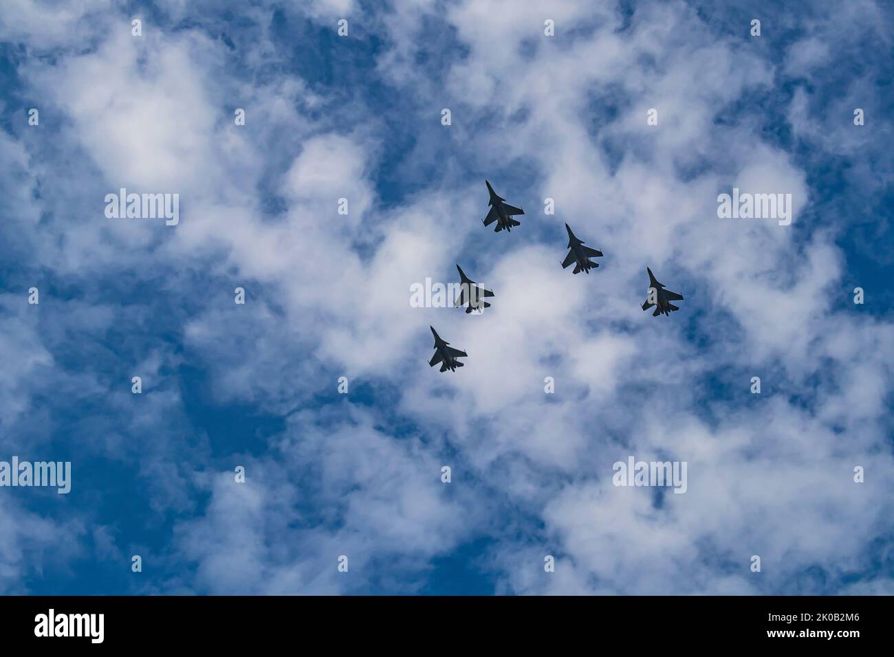 Silhouette of Royal Malaysian Air Force's Sukhoi Su-30MKM fly in formation across blue sky with thin clouds. Stock Photo