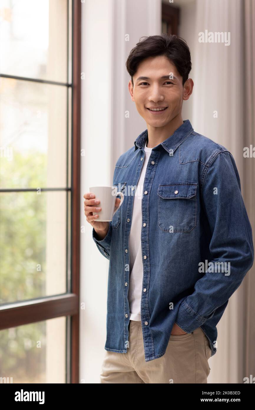 Happy young Chinese man holding coffee Stock Photo
