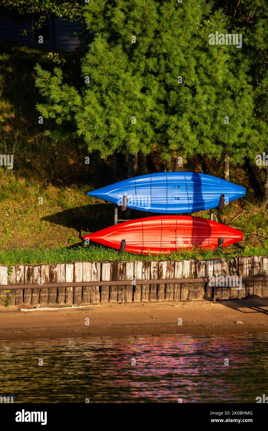 Red and blue kayak stored on a rack next to a Wisconsin lake in summer