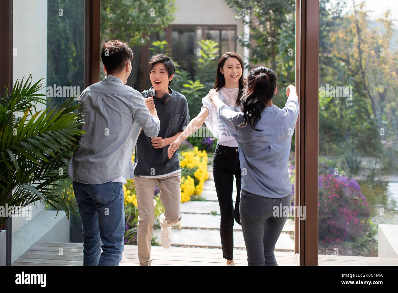Young Chinese couple welcoming guests for party Stock Photo - Alamy