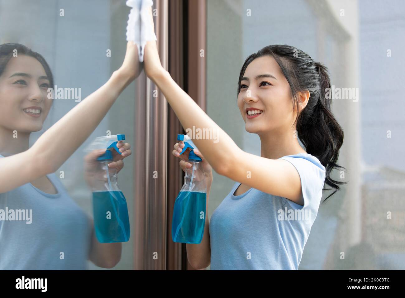 Cheerful young Chinese woman doing housework Stock Photo