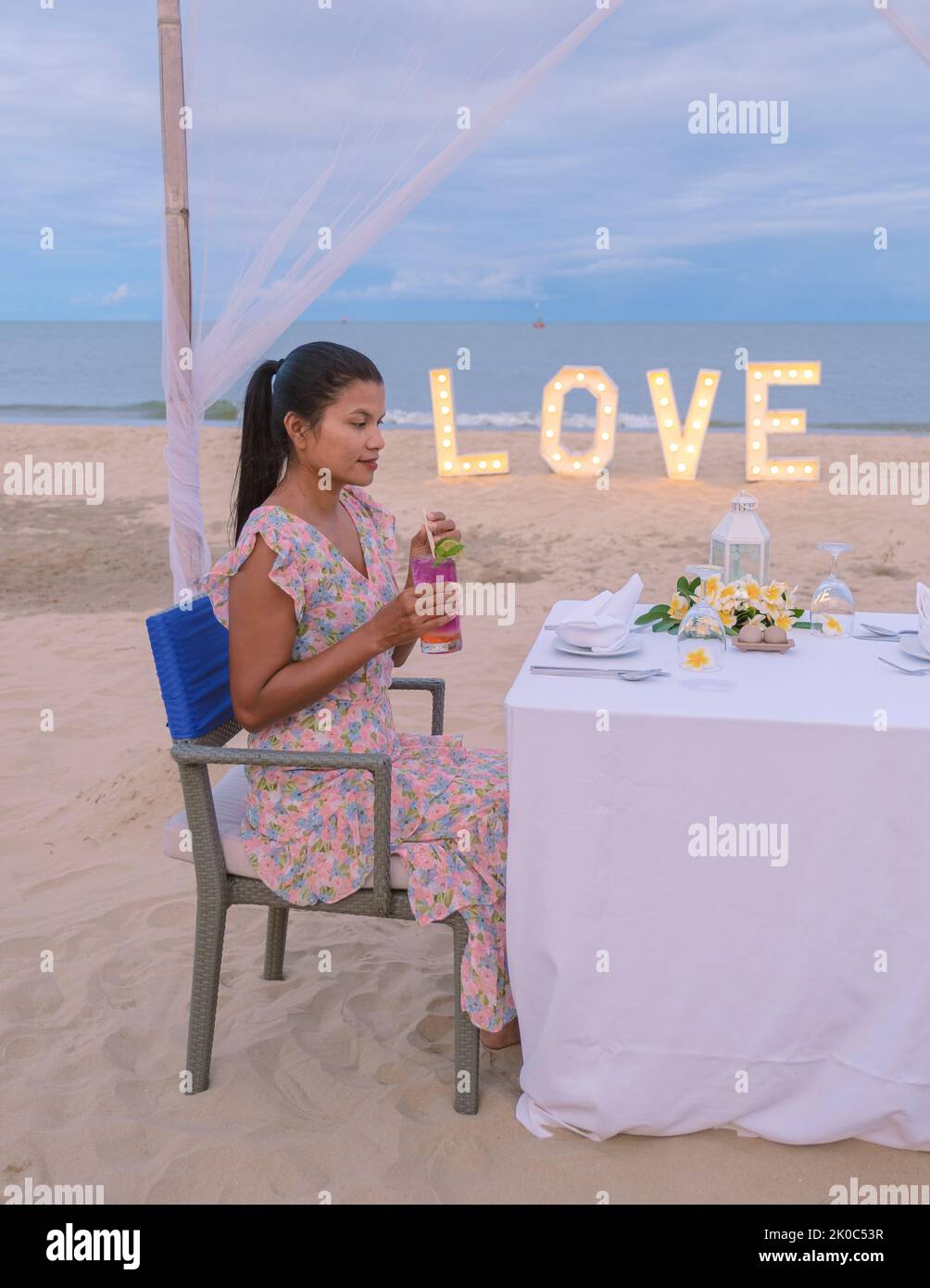 Romantic dinner on the beach of Huahin Thailand, dinner by candle light in Hua Hin , Valentine's concept. Asian women having dinner on the beach during sunset Stock Photo