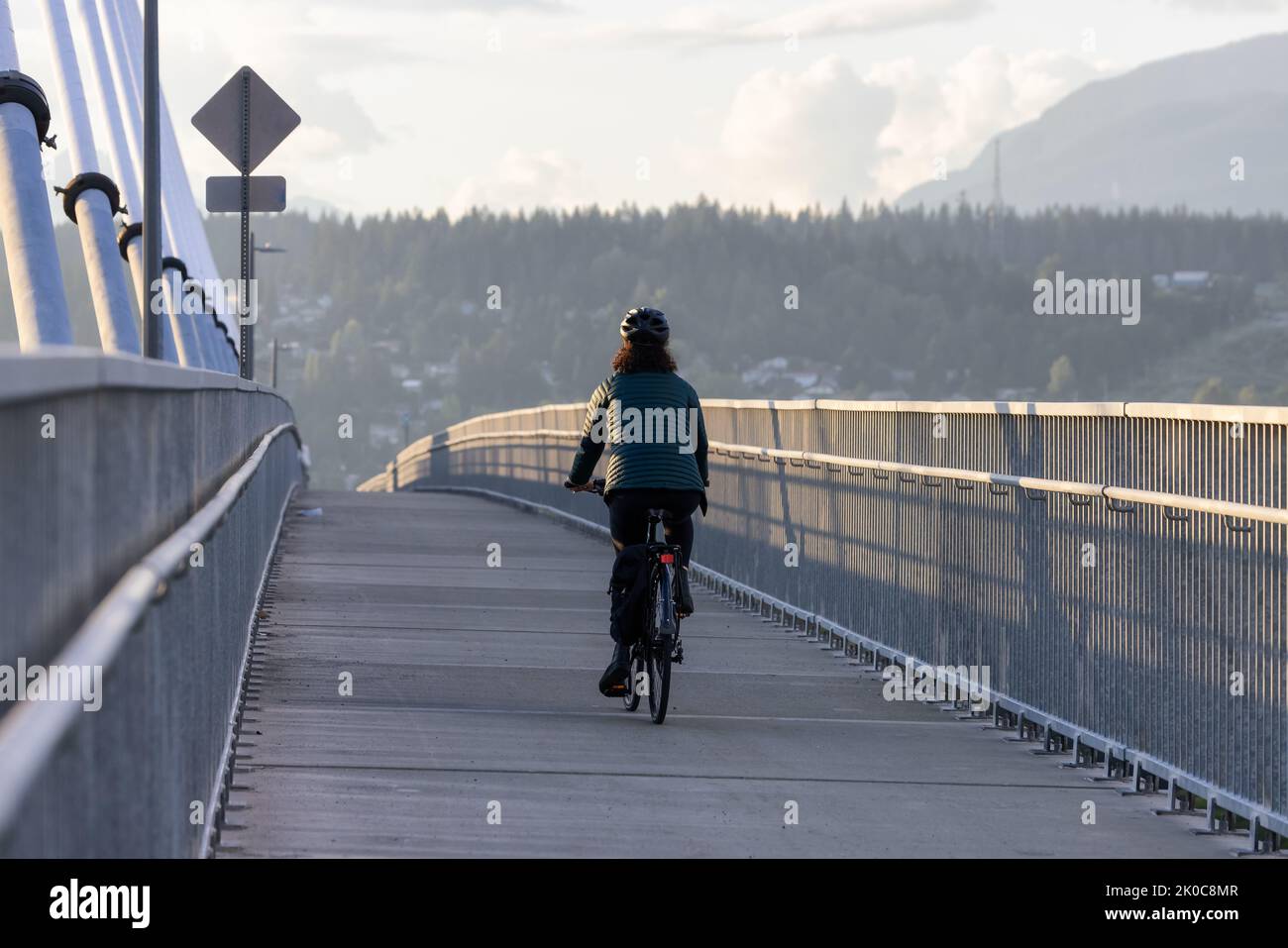 Caucasian Woman riding on a bicycle on a bike lane at Port Mann Bridge Stock Photo