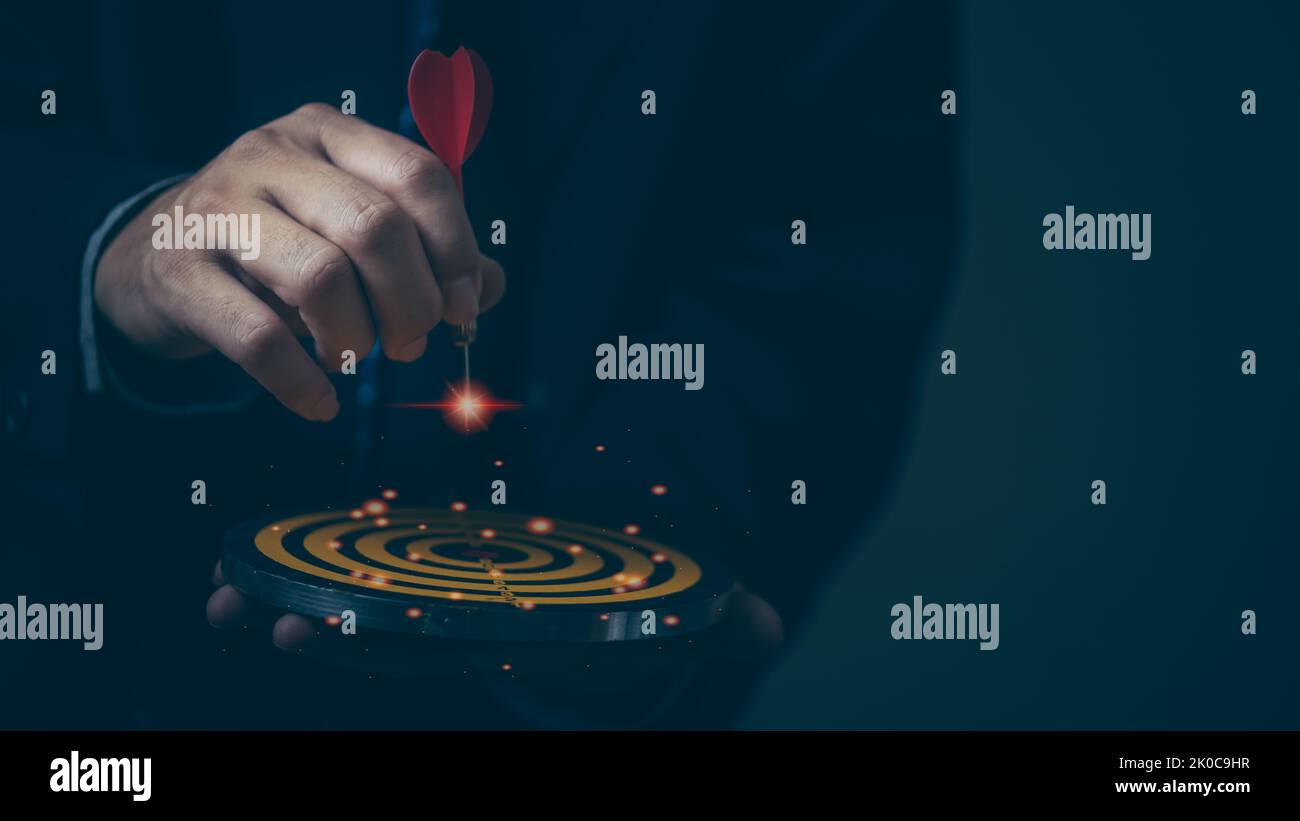 Businessman hand holding red dart to the virtual target dartboard ...