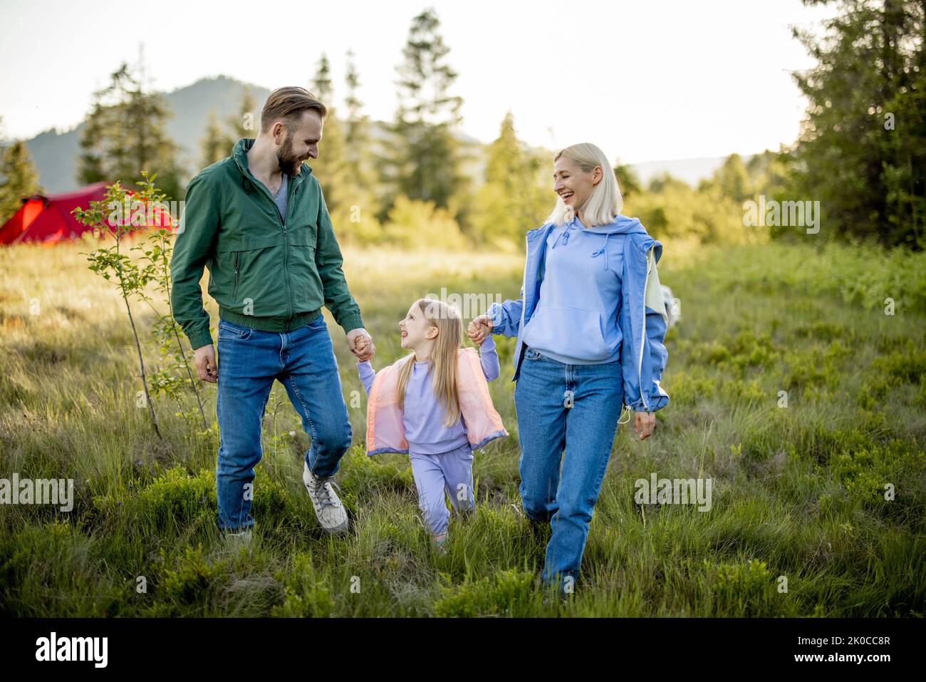 Young caucasian couple with little girl walk together while traveling in the mountains. Happy family spending summer vacation on nature Stock Photo