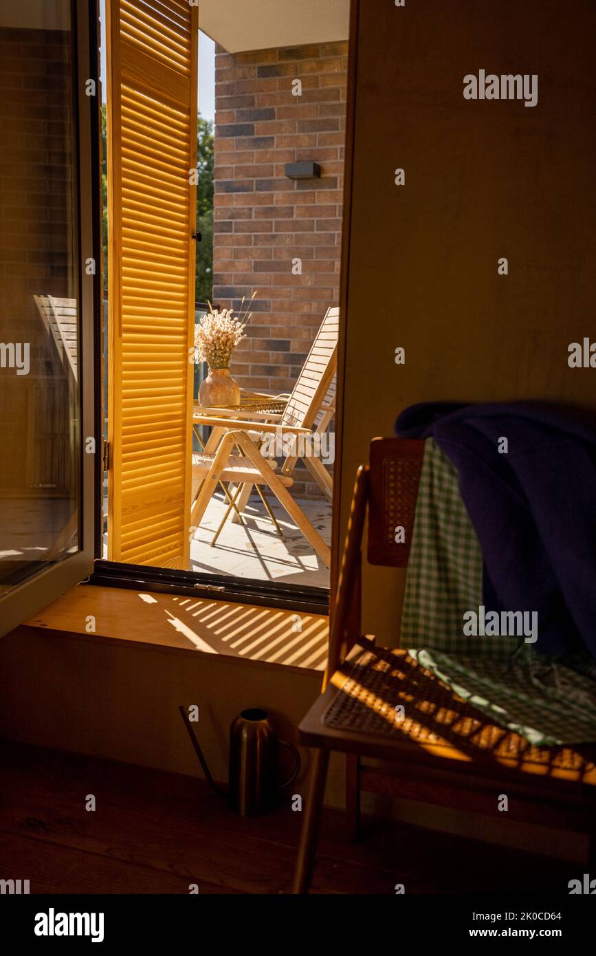 View through the window shutters on balcony with wooden lounge chairs Stock Photo