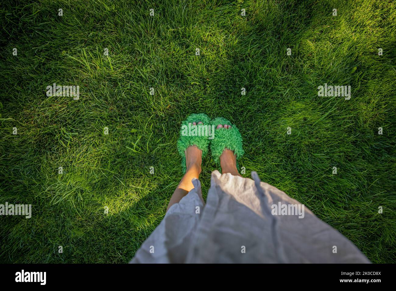 Woman in fluffy slippers on green grass, view from above Stock Photo
