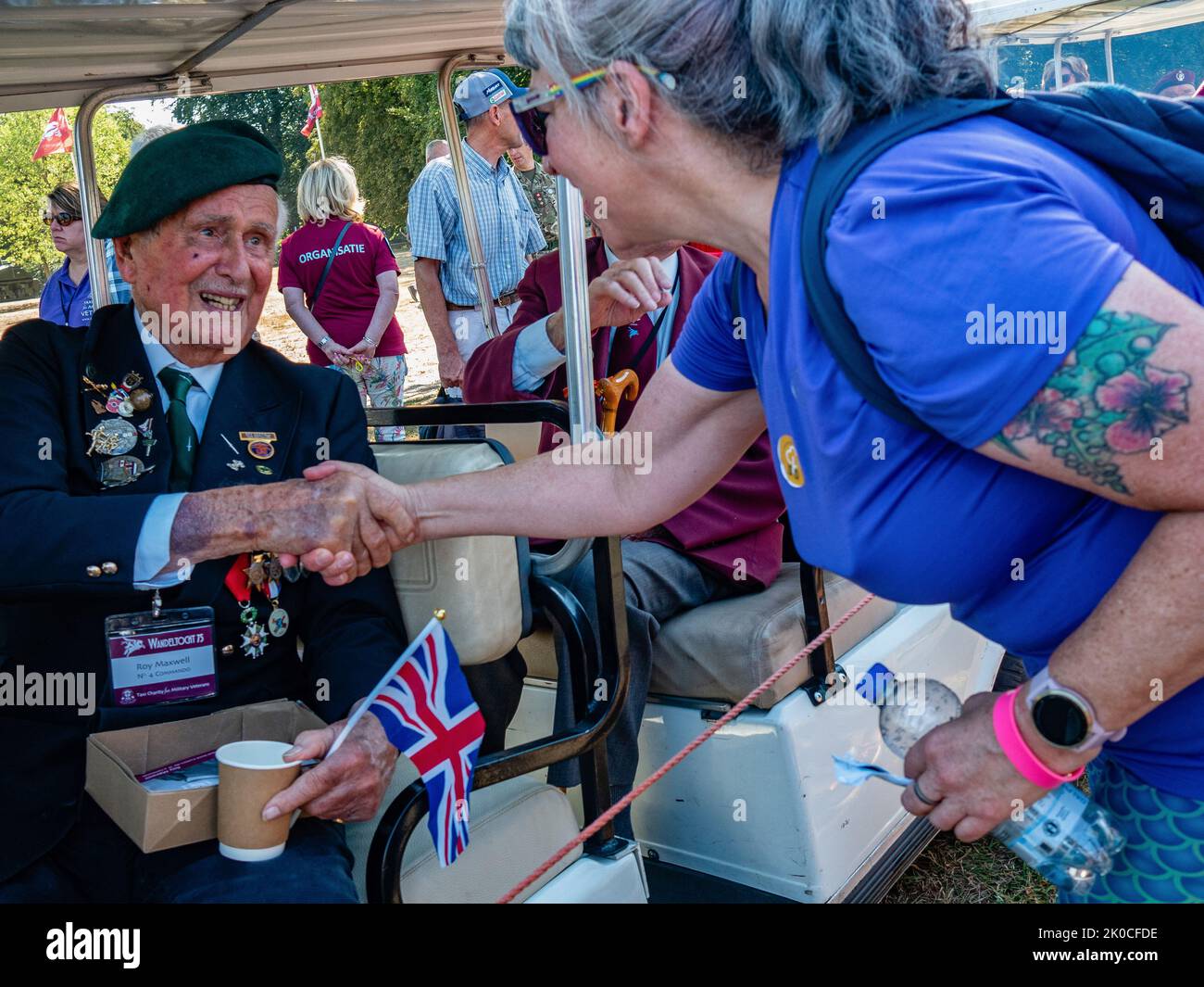 A female participant handshakes with one of the English WW2 veterans