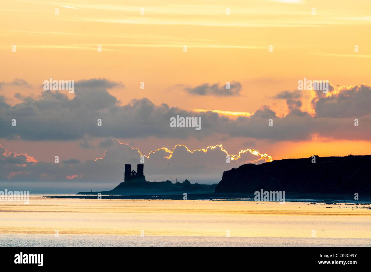 Herne Bay, Kent. 11/09/22. The dawn sky breaking over the sea and the landmark Reculver twin towers of the ruined 12th century church, long used as a navigation aid by seafarers. Some ground drifting in over the headland which was quickly dispersed when the sun rose. Credit-Malcolm Fairman, Alamy Live News. Stock Photo