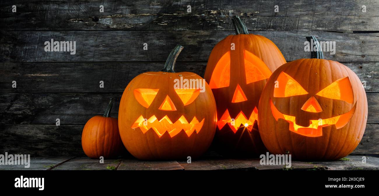 Group of Halloween pumpkins with candles inside on wooden background Stock Photo